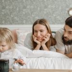 A loving family of three enjoying time together in a peaceful bedroom setting.