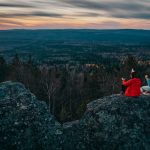 Group enjoying sunset view on a mountain top in Russia wearing party hats in winter attire.