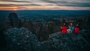 Group enjoying sunset view on a mountain top in Russia wearing party hats in winter attire.