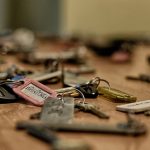 Macro shot of various metallic keys scattered on a wooden surface.