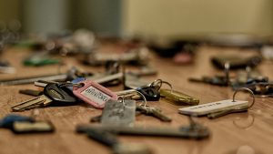 Macro shot of various metallic keys scattered on a wooden surface.